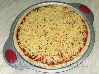 Тесто, соус и сыр на форме для запекания пиццы